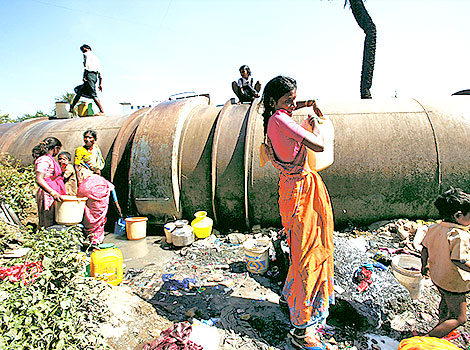 Slum dwellers collecting water from leaking pipes (Source: Hindustan Times)